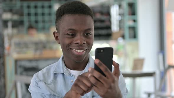 Portrait of Cheerful Young African Man Using Smartphone