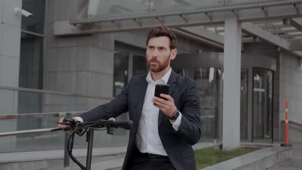 Caucasian Man in Formal Suit Paying for Scooter Rent Using Mobile Application Stand with Smartphone