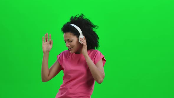 Portrait of Young Female African American Dancing and Enjoying Music in Big White Headphones