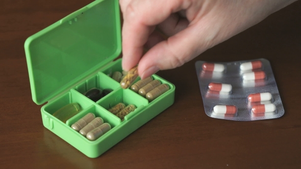 Woman's Hand Puts Capsules Pills In Container