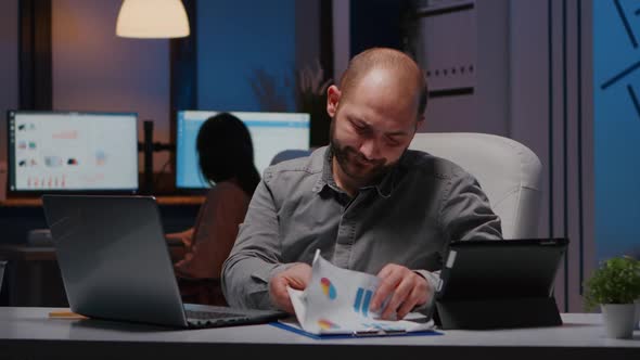 Workaholic Focused Businessman Analysing Marketing Graphics on Clipboard