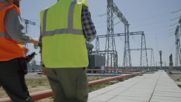 Male Engineers Walking and Talking on Power Plant
