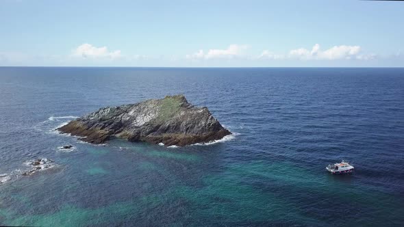 Boat Anchored Near The Chick Island Surrounded By Calm Blue Sea In Newquay, Cornwall, England. - aer