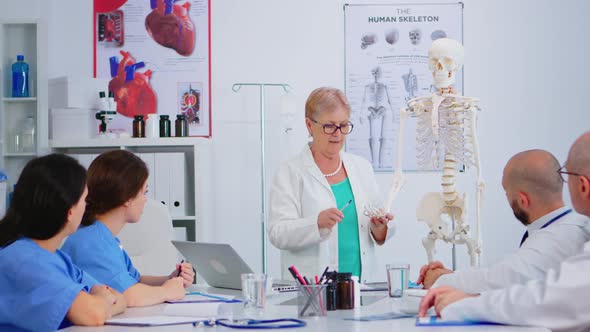 Elderly Woman Doctor Showing the Work of Human's Hand on Skeleton Model