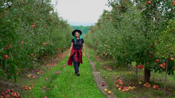 Pretty Unusual Woman with Blue Dyed Hair Walking Alone Between Trees in Apple Garden at Autumn