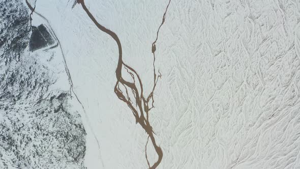 Drone Over Snow Covered Landscape With Frozen Braided Riverbed