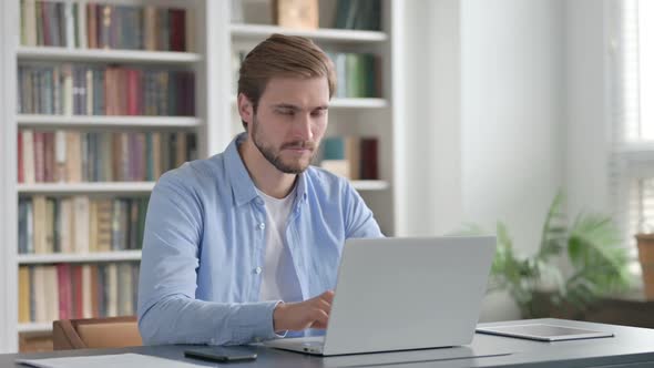 Man Showing Thumbs Up Sign While Using Laptop at Work