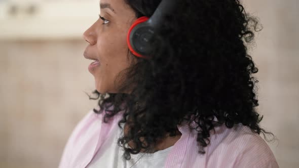 Closeup Joyful Young Woman in Headphones Singing Dancing Cooking in the Morning at Home