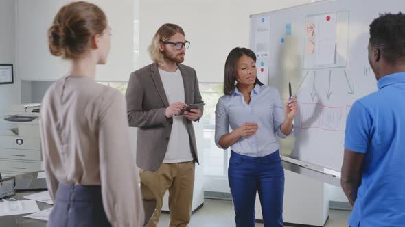 Diverse Startup Team Discussing Project in Boardroom Analyzing Flowchart on Board