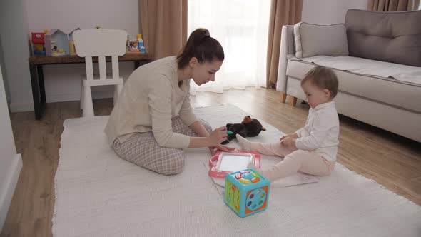 Happy Family Mother Teaching Cute Child Girl Playing on Warm Floor at Home Daughter Learning Drawing