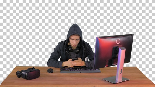 Hooded hacker using laptop and smartphone, Alpha Channel