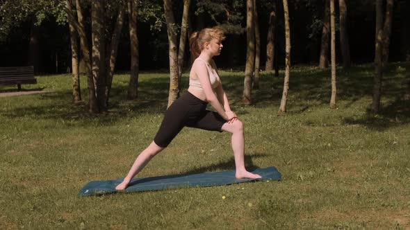 A Young Girl is Doing Yoga in a Public Park in the Fresh Air
