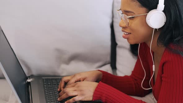 Young African Woman in Headphones with Laptop Working at Home