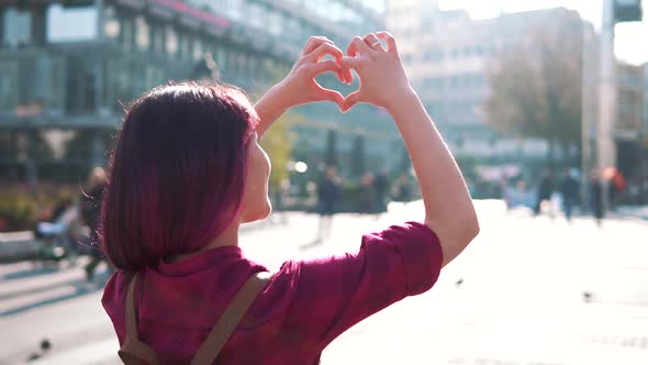 Woman Holding a Heartshape in Front Og a City