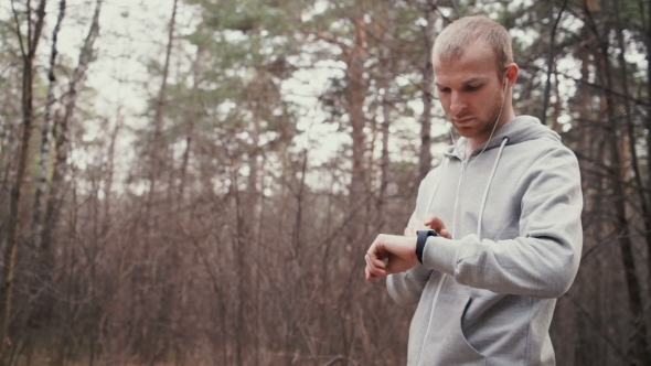Man Running In Forest Woods Training And Look At Smart Watches.