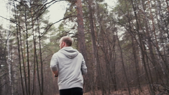 Man Running In Forest Woods Training And Look At Smart Watch