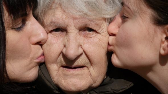 Women are Kissing Grandmother on the Cheeks