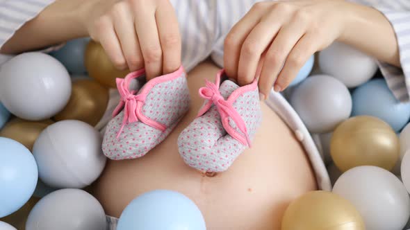 Pregnant Woman Playing With Booties For Her Future Baby. Close-Up