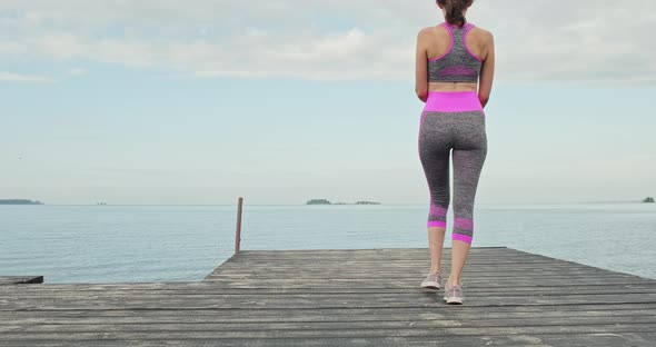 Young Girl in Tracksuit Goes To the Pier and Does Sports Yoga