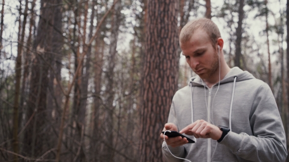 Young Handsome Runner With Smart Phone Outside in Sunny Autumn Nature