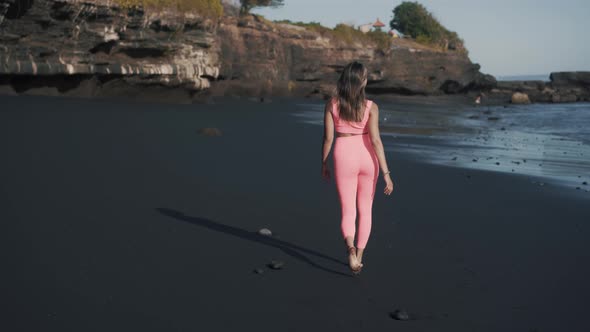 Back View of Young Caucasian Fitness Model Walking Down the Seashore