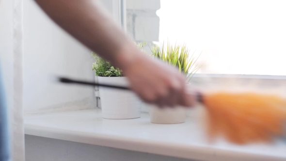 Woman With Duster Cleaning Window Sill At Home 1