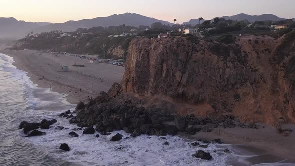 AERIAL: Flight Over Malibu, California View of Beach Shore Line Pacific Ocean at Sunset with