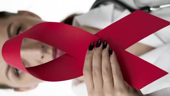 Vertical Shot Close Up Serious Beautiful Doctor Holding AID HIV Red Ribbon Symbol of Cancer