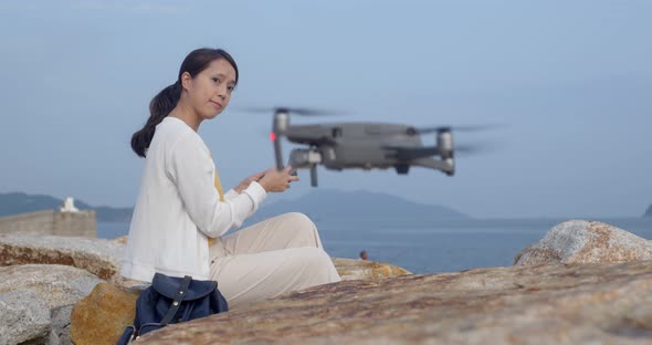 Woman fly a drone and stand at the sea side