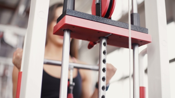 Young Woman Flexing Muscles On Cable Gym Machine