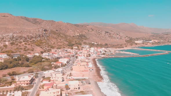 Drone flying over small town i Greece right by the water.