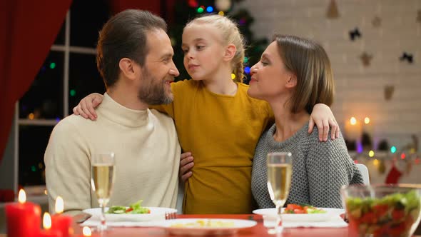Happy Family Having Xmas Dinner, Daughter Kissing Parents, Decorations Twinkling