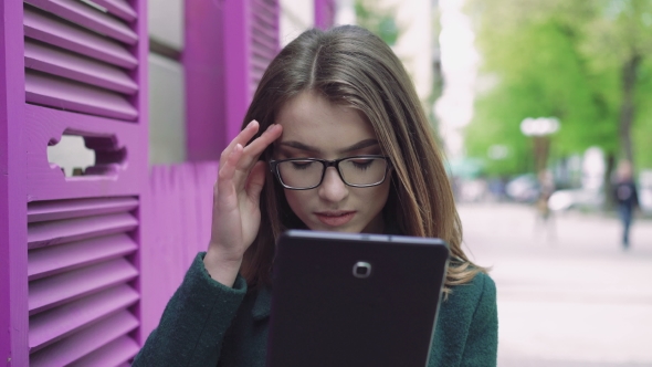 Portrait of Young Woman Using a Tablet on a Street 