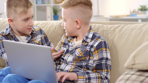 Agitated Caucasian Twins Typing on Laptop alt