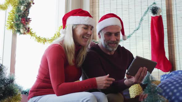 Happy caucasian mature couple making video call in room full of christmas decorations