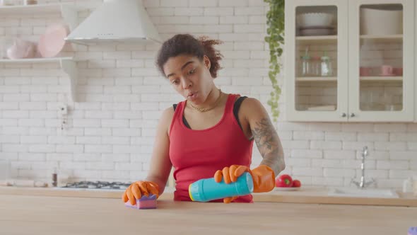 Tired Woman Polishing Table with Cleaning Detergent