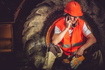 Businessman Making Business Call While Seating Inside Heavy Duty Bulldozer Tire.