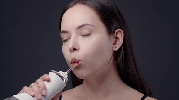 Young Woman Cleaning Her Teeth with Water Flosser