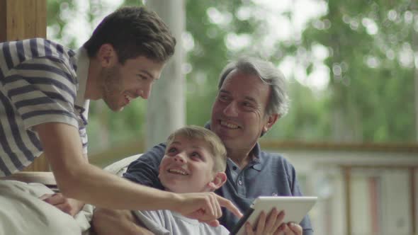 Boy with father and grandfather using digital tablet