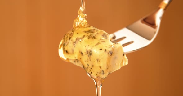 Liquid Organic Honey Dripping on a Fork with Dorbly Cheese on a Light Background