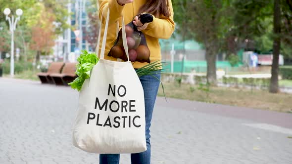 A Woman Puts Vegetables and Fruits in a Fruit Bag with the Inscription No More Plastic