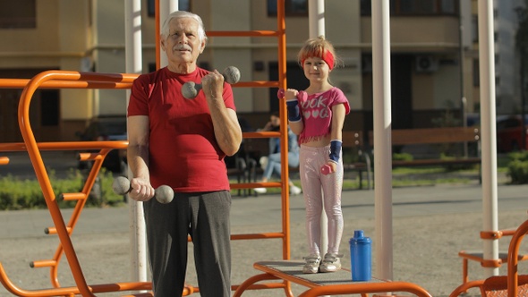Granddaughter and Grandfather Doing Fitness Exercises with Dumbbells. Senior Man with Child Kid Girl