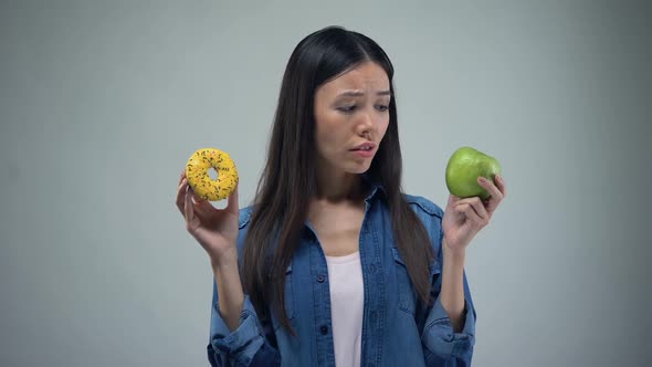 Hungry Girl Trying to Choose Between Donut and Apple, Healthy Eating, Temptation