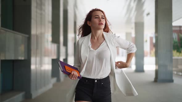 Beautiful business woman with red hair in fashion clothes walk work near office