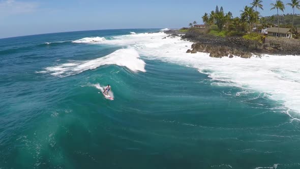 Aerial view of a man sup stand-up paddleboard surfing in Hawaii.