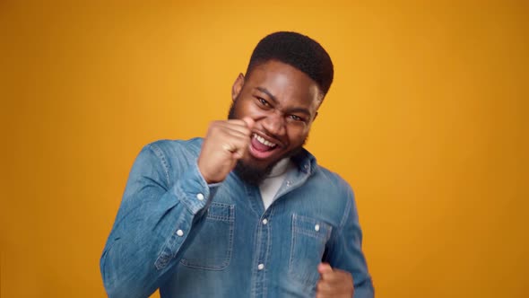 Pleased African Man in Shirt Dancing Against Yellow Background