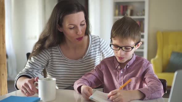 Young Mother Helps Her Son Do Homework at Table During Selfisolation in Apartment Room Spbd