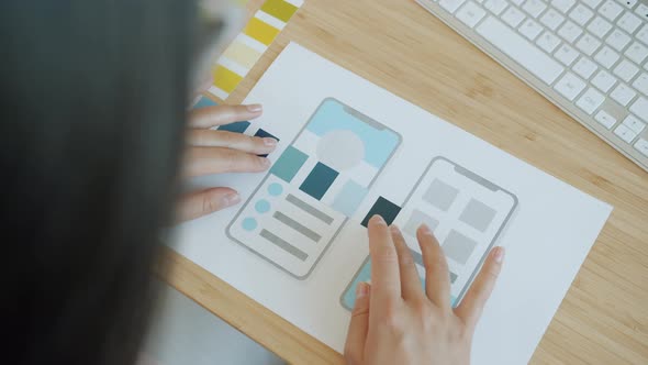 Closeup of Female Designer's Hands Using Color Palette and Paper with Smartphone Application Screen