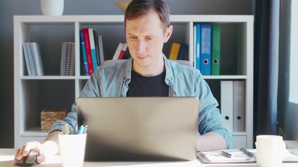 Young male entrepreneur works at home office at the computer.