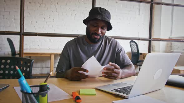 Thoughtful African American Man Writing Plan in Office Having Problems with Inspiration and